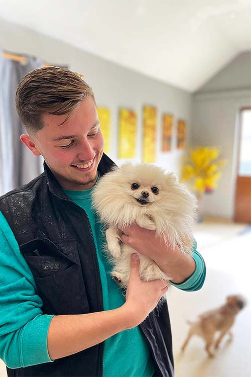 Canine Carer cuddling a very cute, tiny white fluffy Pomeranian