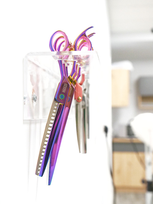Iridescent colourful scissors set slotted into a clear acrylic wall holder
